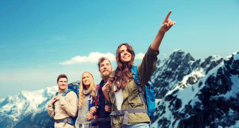 Groupe d'ami(e)s avec une femme qui oriente son doigt vers les hauteurs, en second plan la montagne